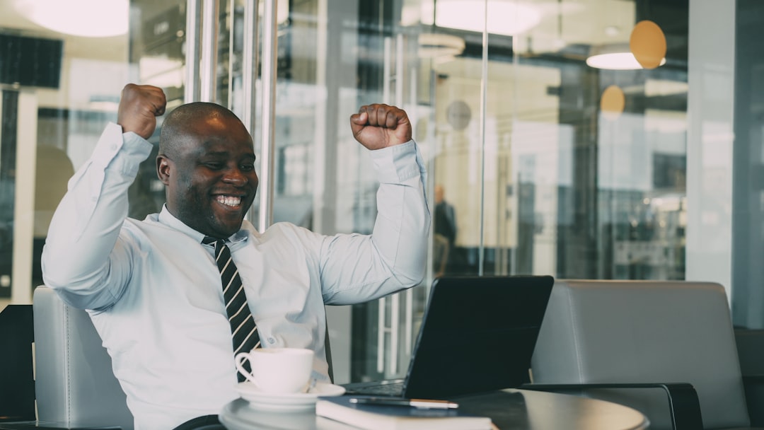 wrote my book — Man celebrating success in office with laptop.