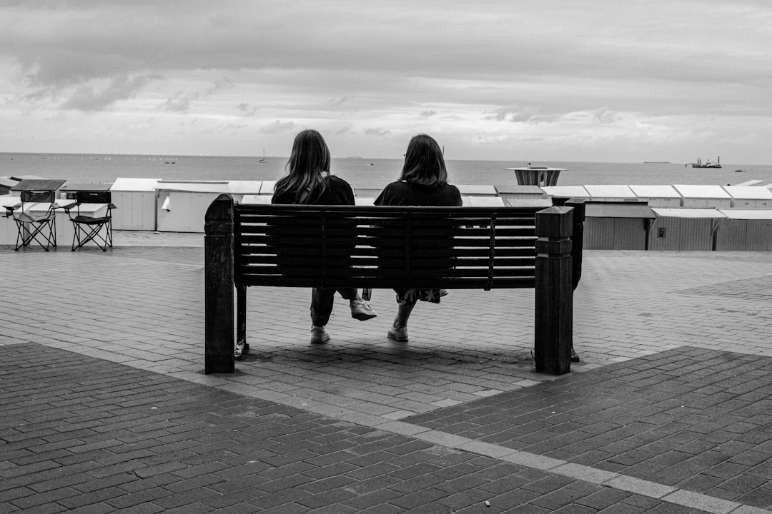 prison communication — Two people sit on a bench overlooking the ocean.